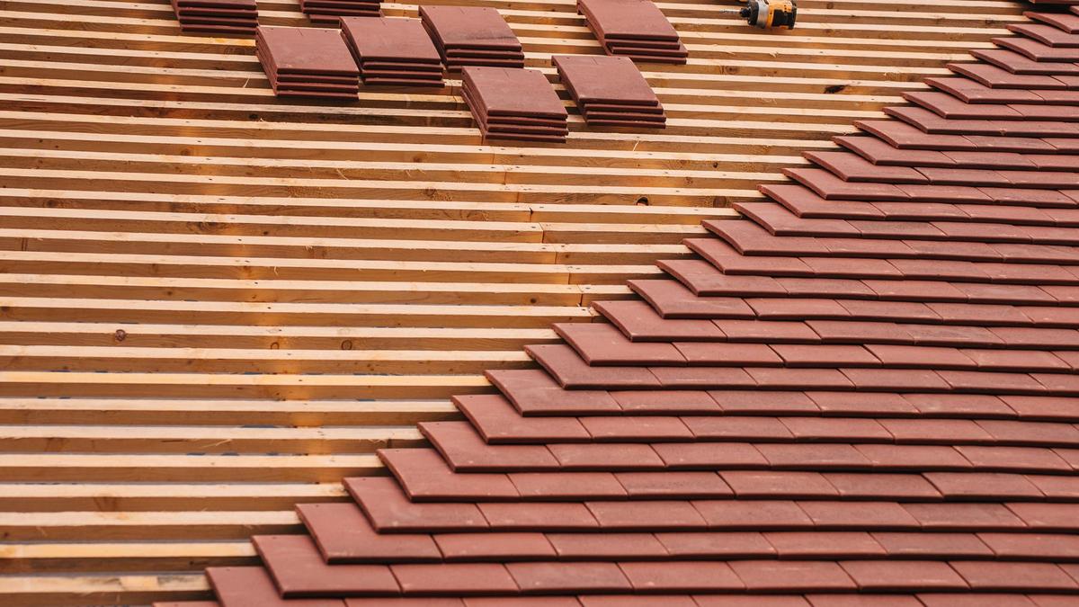 Couvreur posant des tuiles sur un chantier de rénovation de toiture