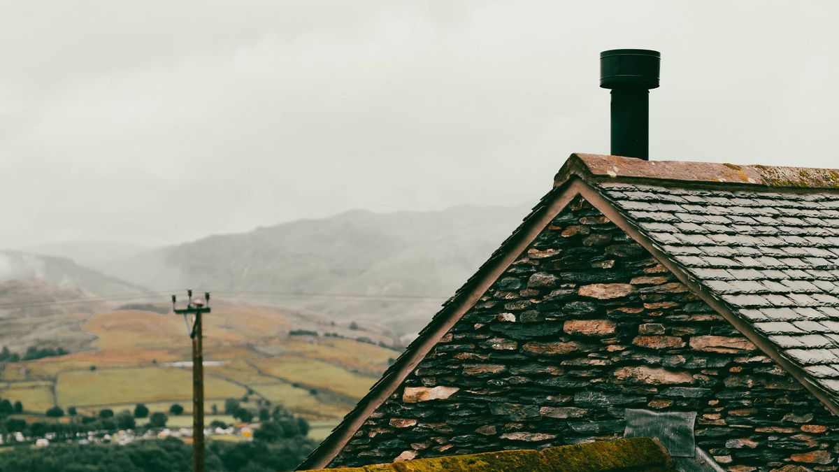 Maison au toit de lauze dans la brume sur un plateau d'altitude
